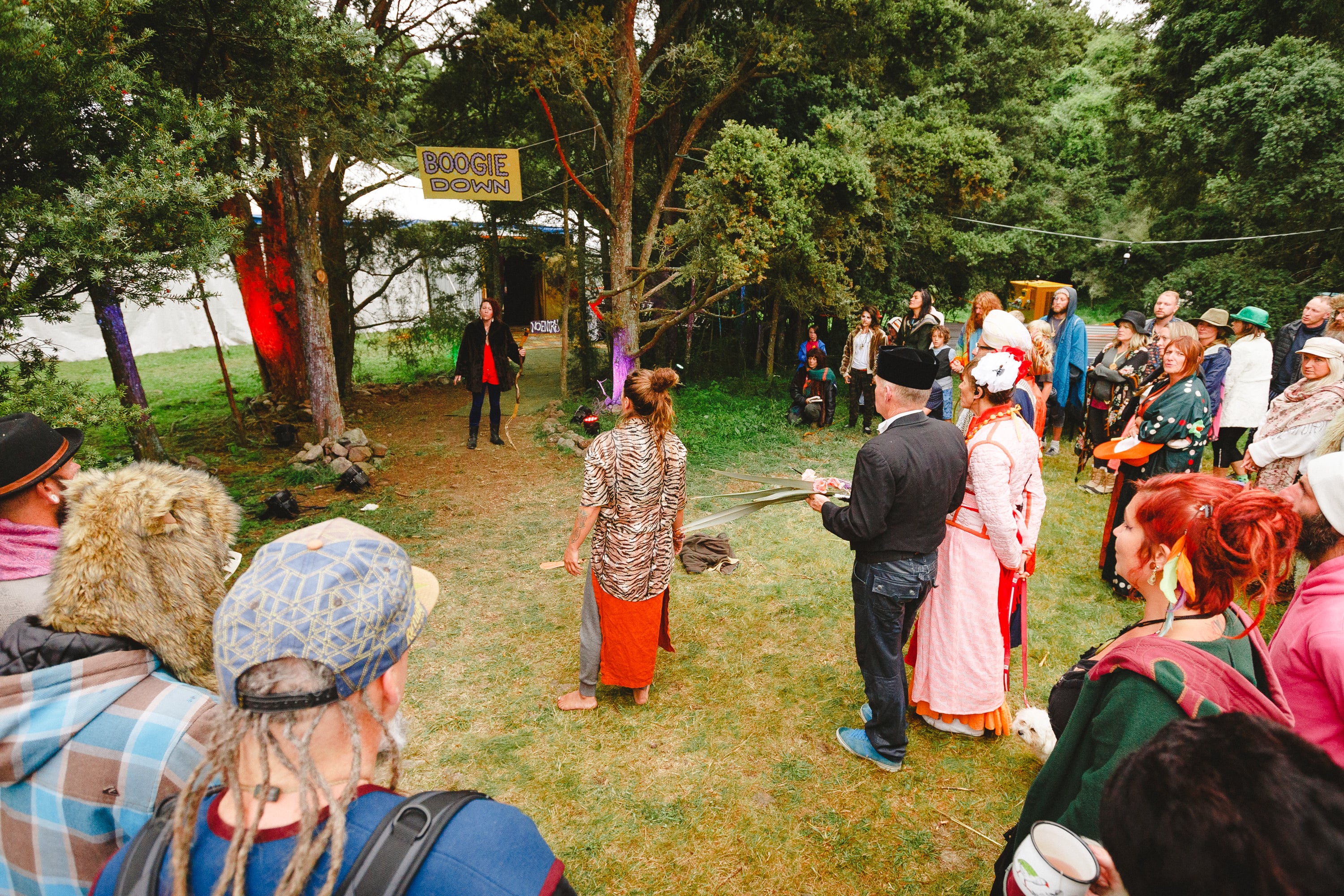 Costumed audience gathered for an outdoor performance in the woods.