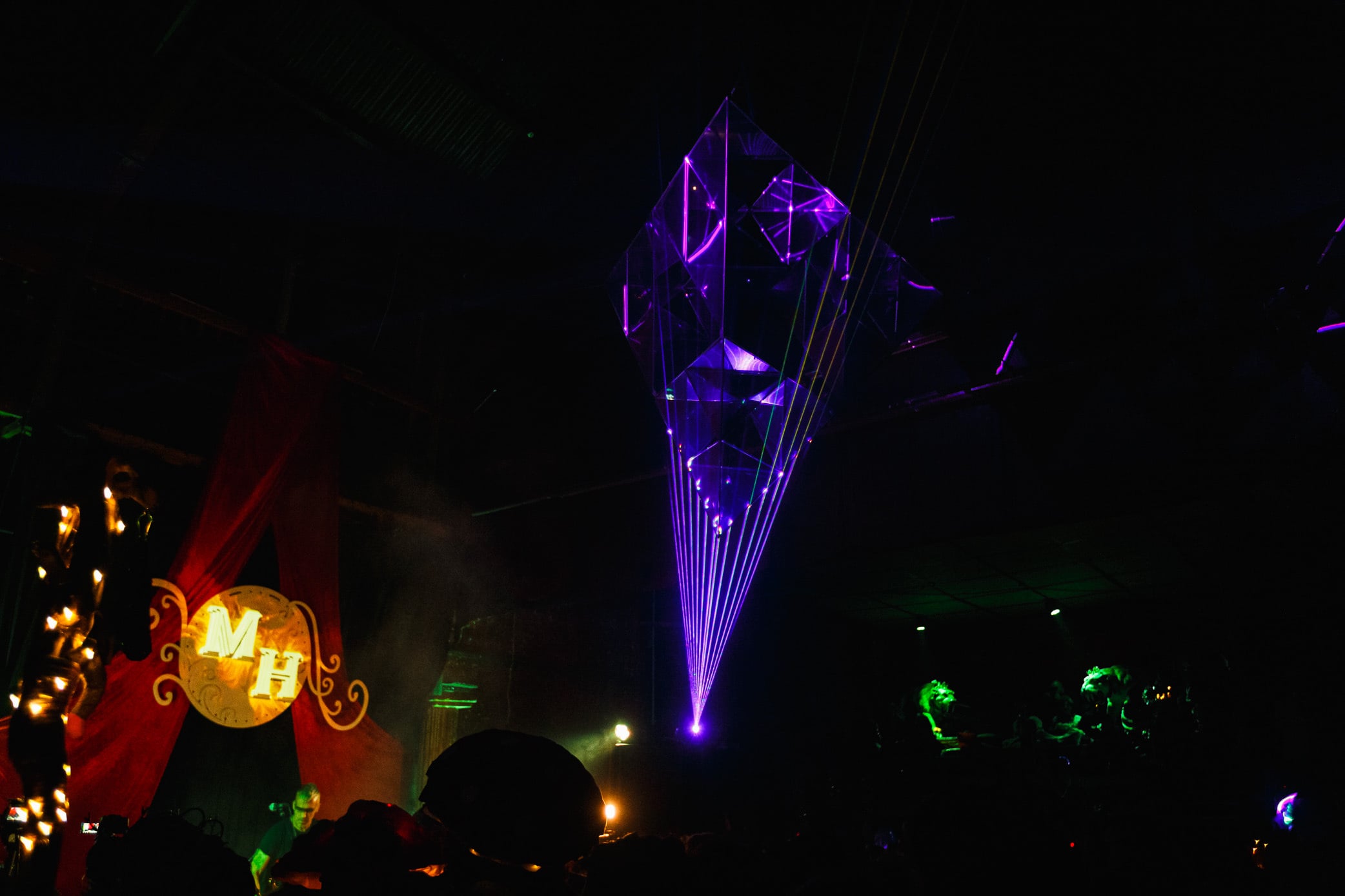 Laser-lit crystal sculpture above a crowd.
