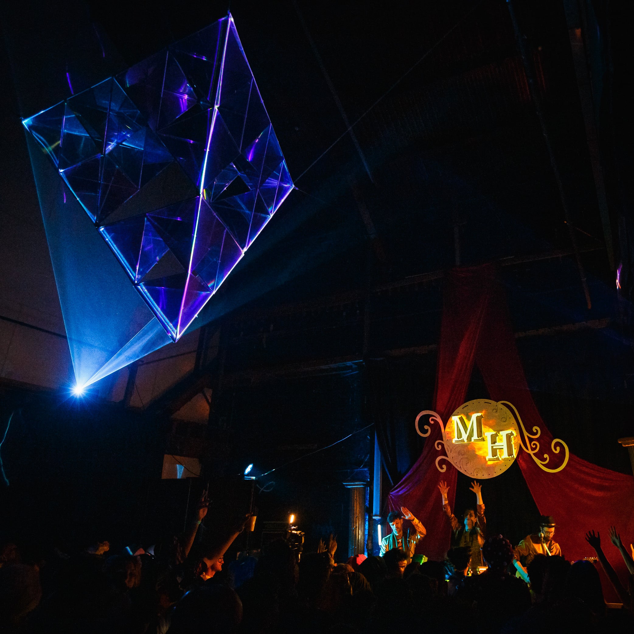 Geometric light installation glowing blue over an audience.