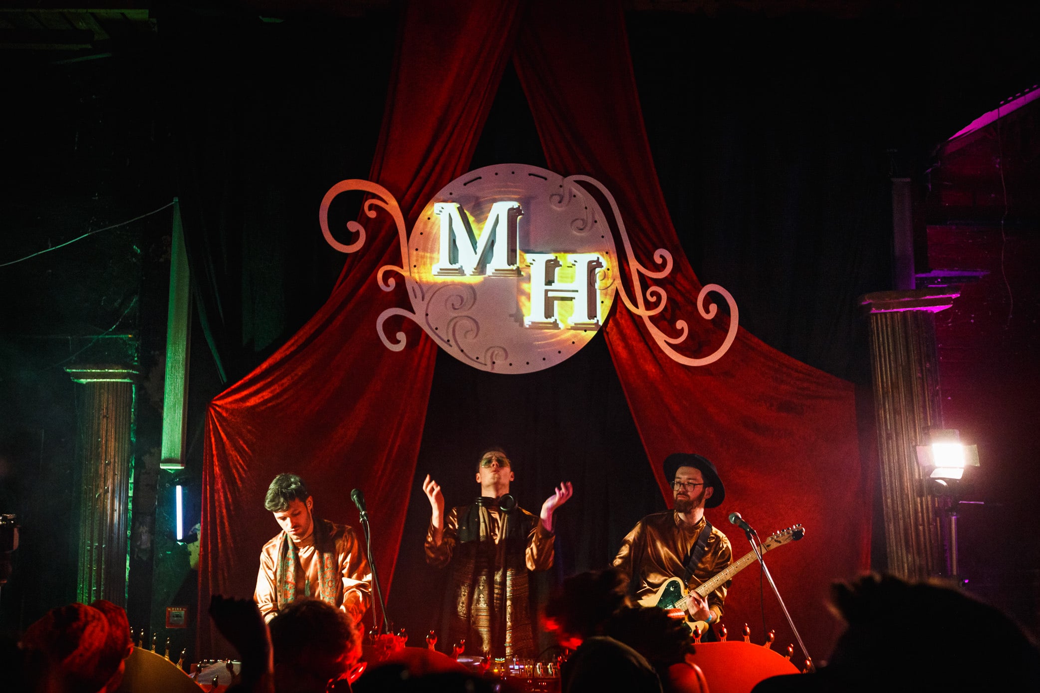 Band performing on an ornate red-curtained stage.