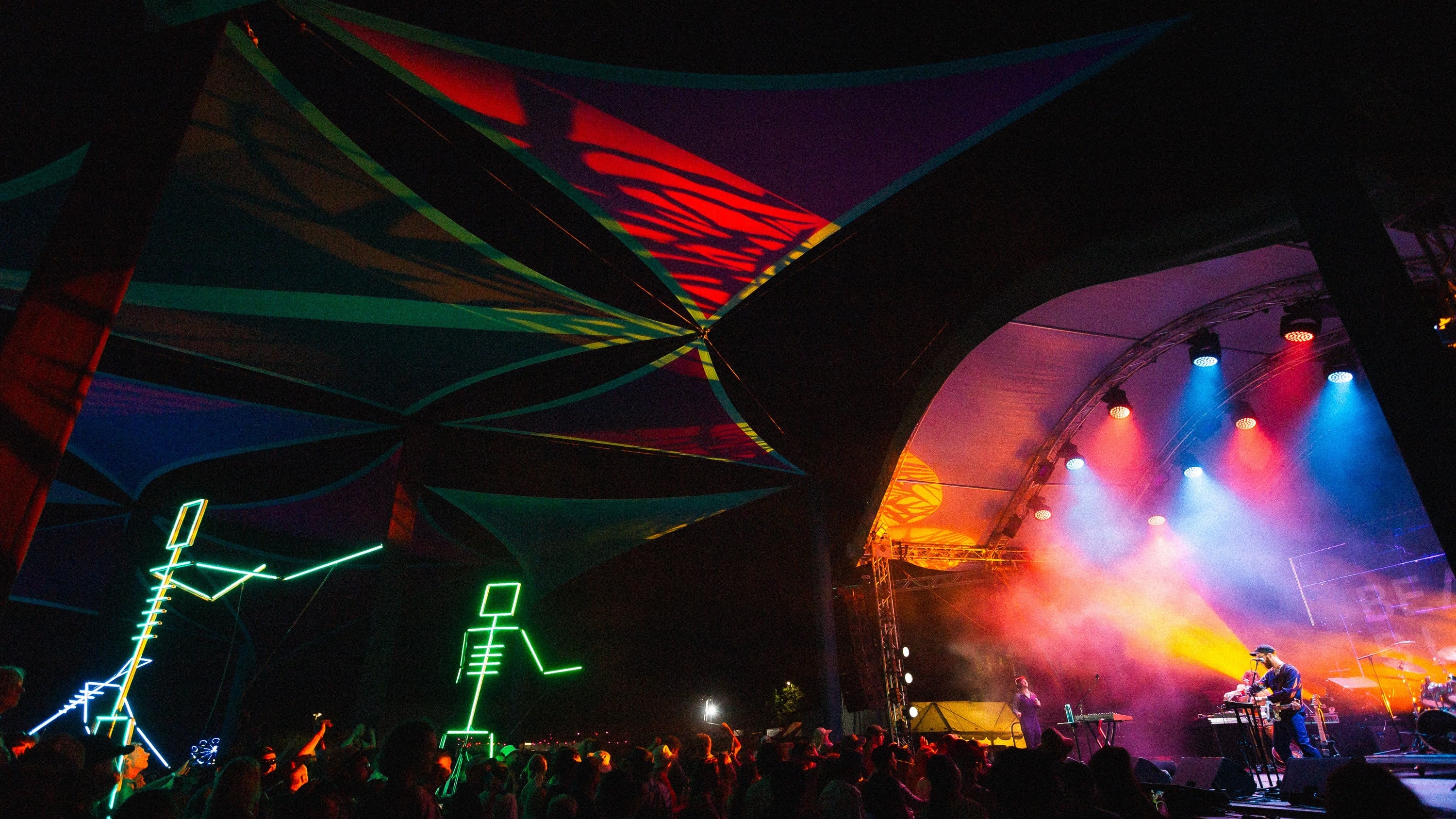 Outdoor festival stage framed by shade sails and figure lights.