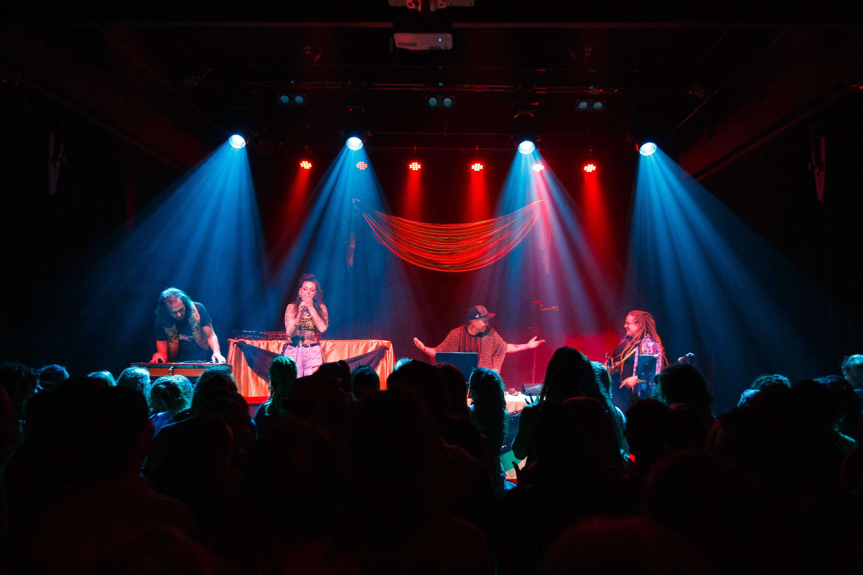 Four performers on stage under blue spotlights.