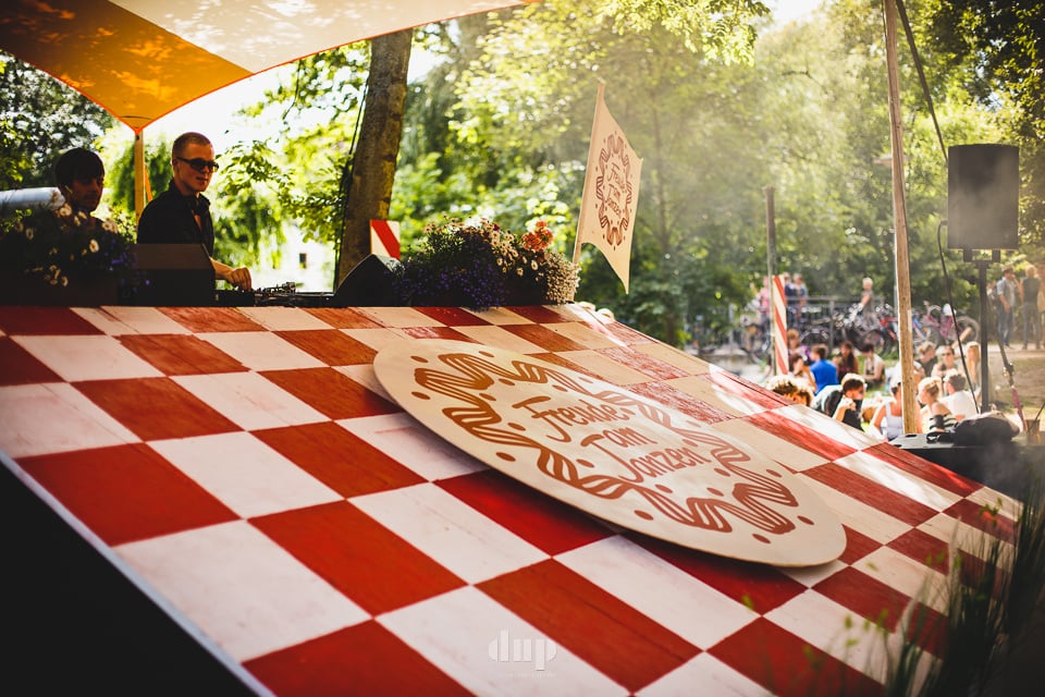 DJs playing from a red-checked stage at a forest festival.