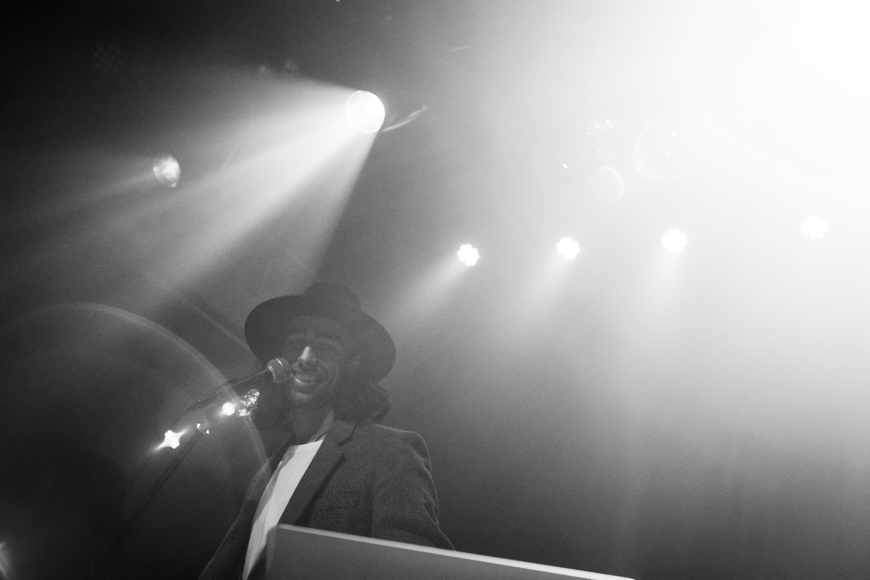 Performer in a hat cutting through stage haze, black and white.