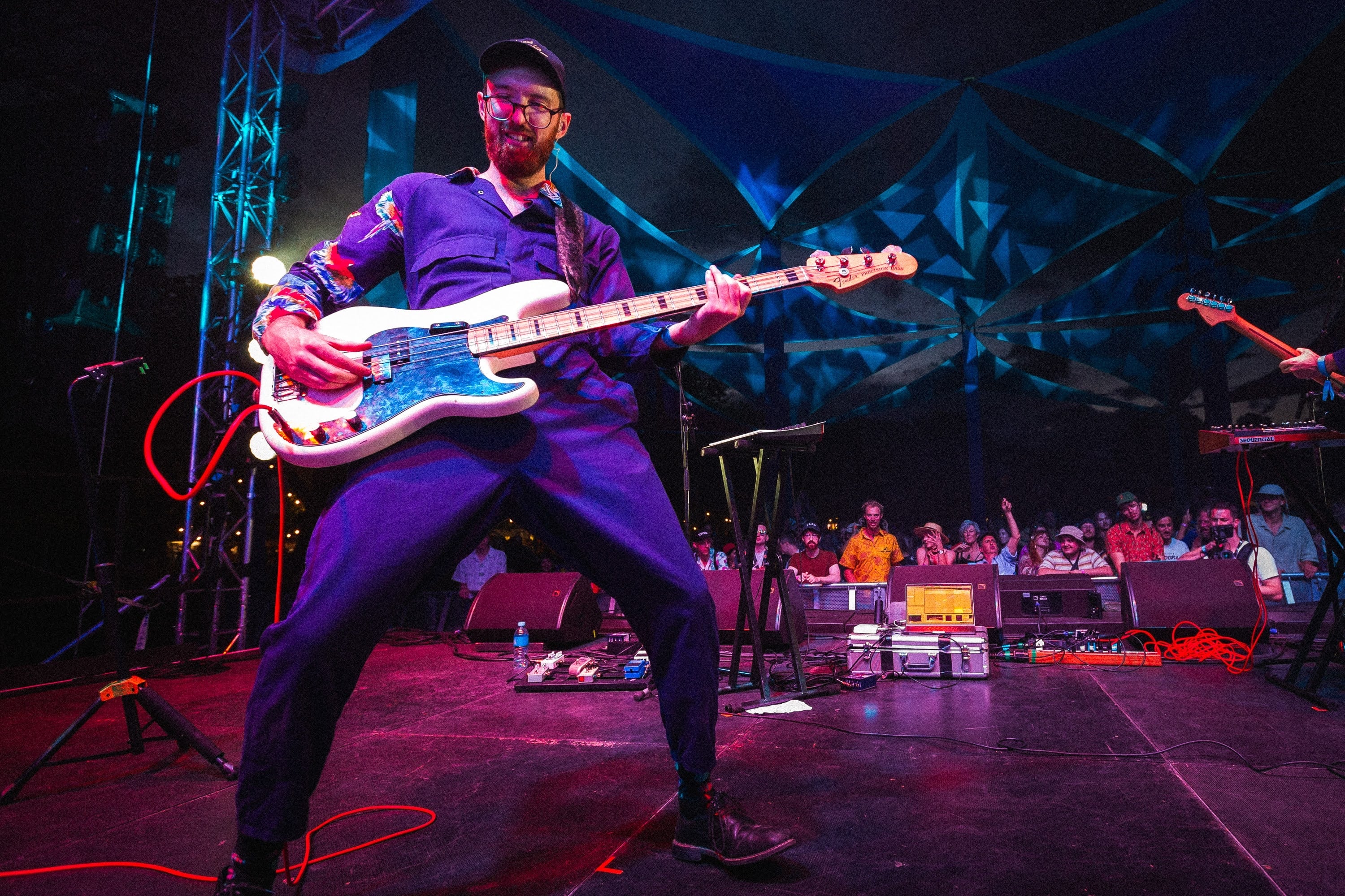 Bassist mid-stride on a festival stage.