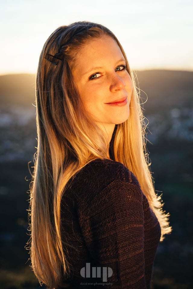 Woman backlit by a low sun on a hillside.