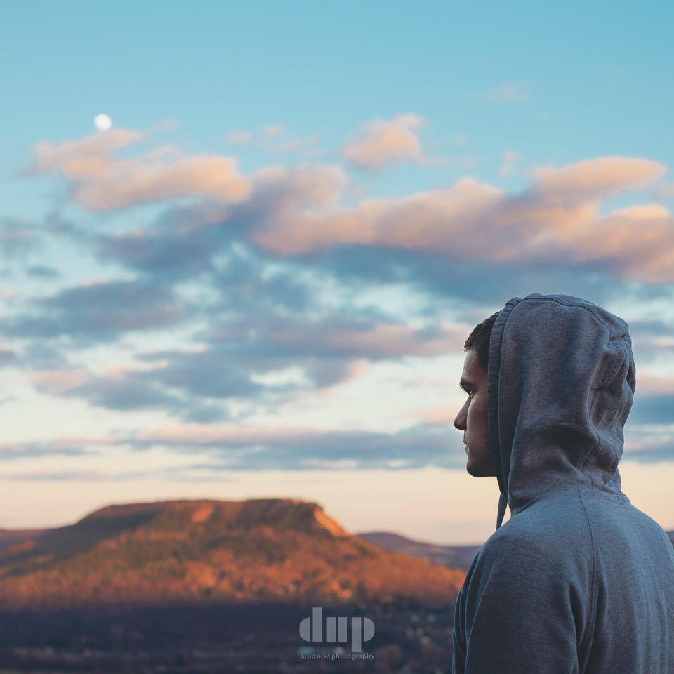 Musician in profile against a sunset ridgeline.