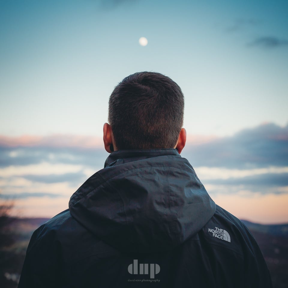 Musician from behind, looking out over the valley at dusk.
