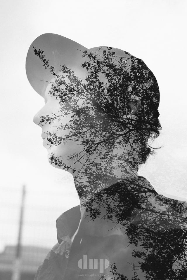 Double-exposure portrait of a profile filled with bare winter trees, black and white.