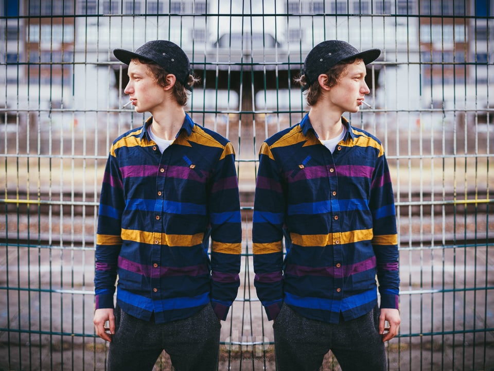 Mirrored promo portrait of a musician in a striped shirt.