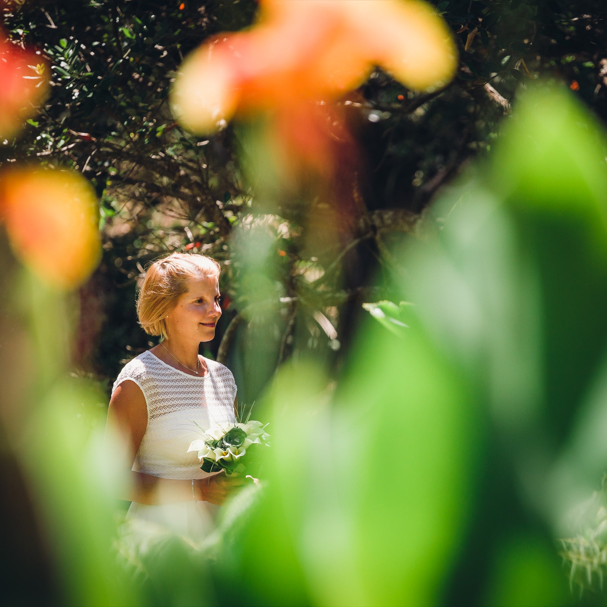 Bride seen through orange flowers in a garden.
