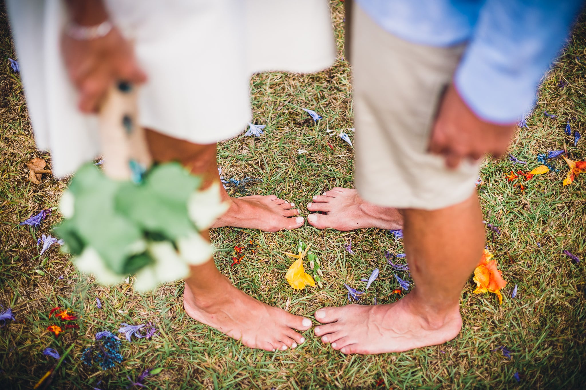 Barefoot couple on grass scattered with petals.