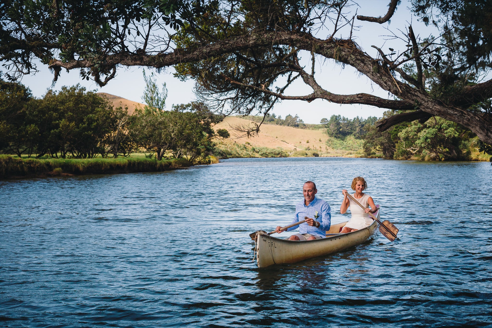 Couple paddling a canoe on a river.