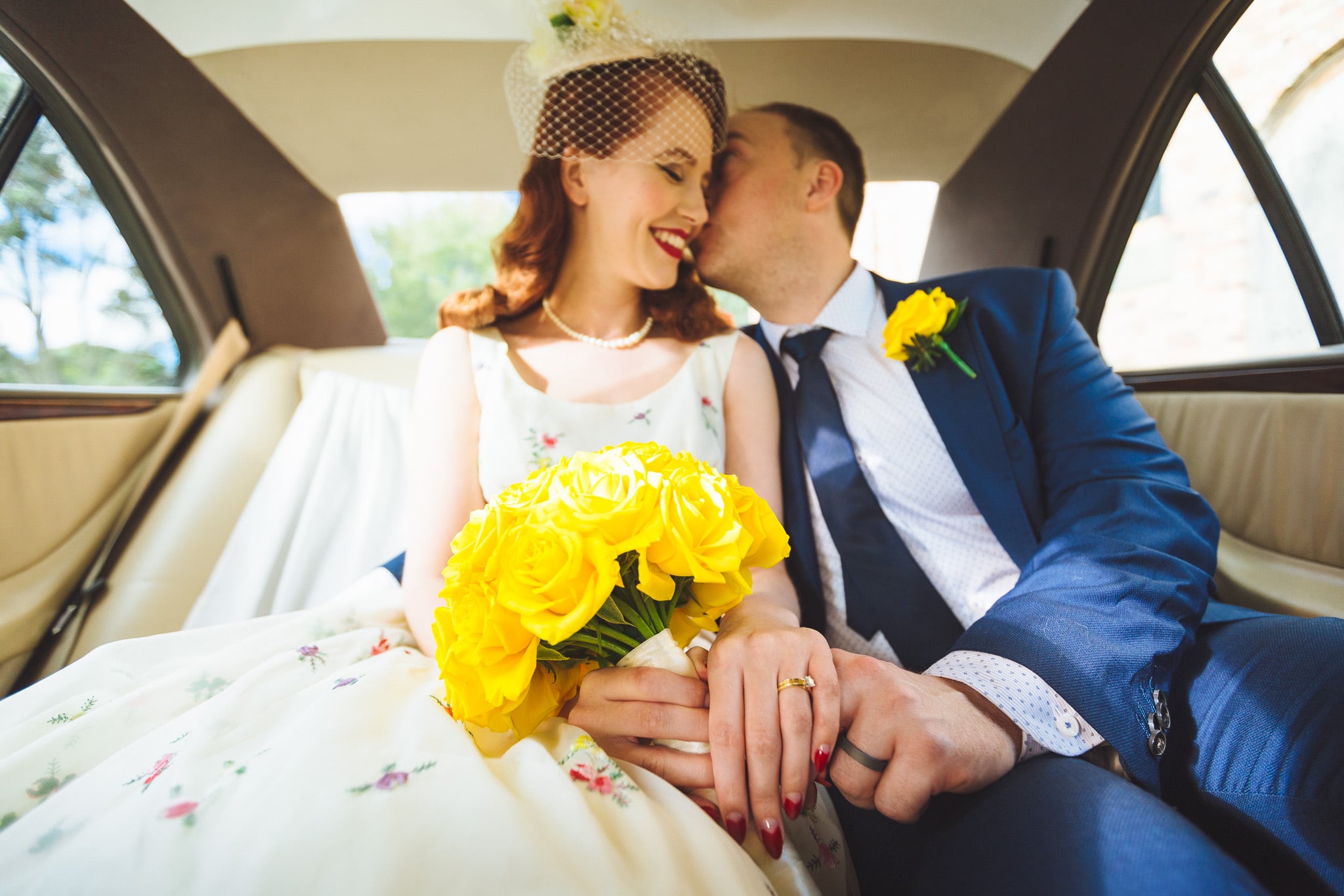 Couple kissing in the back seat of a vintage car.