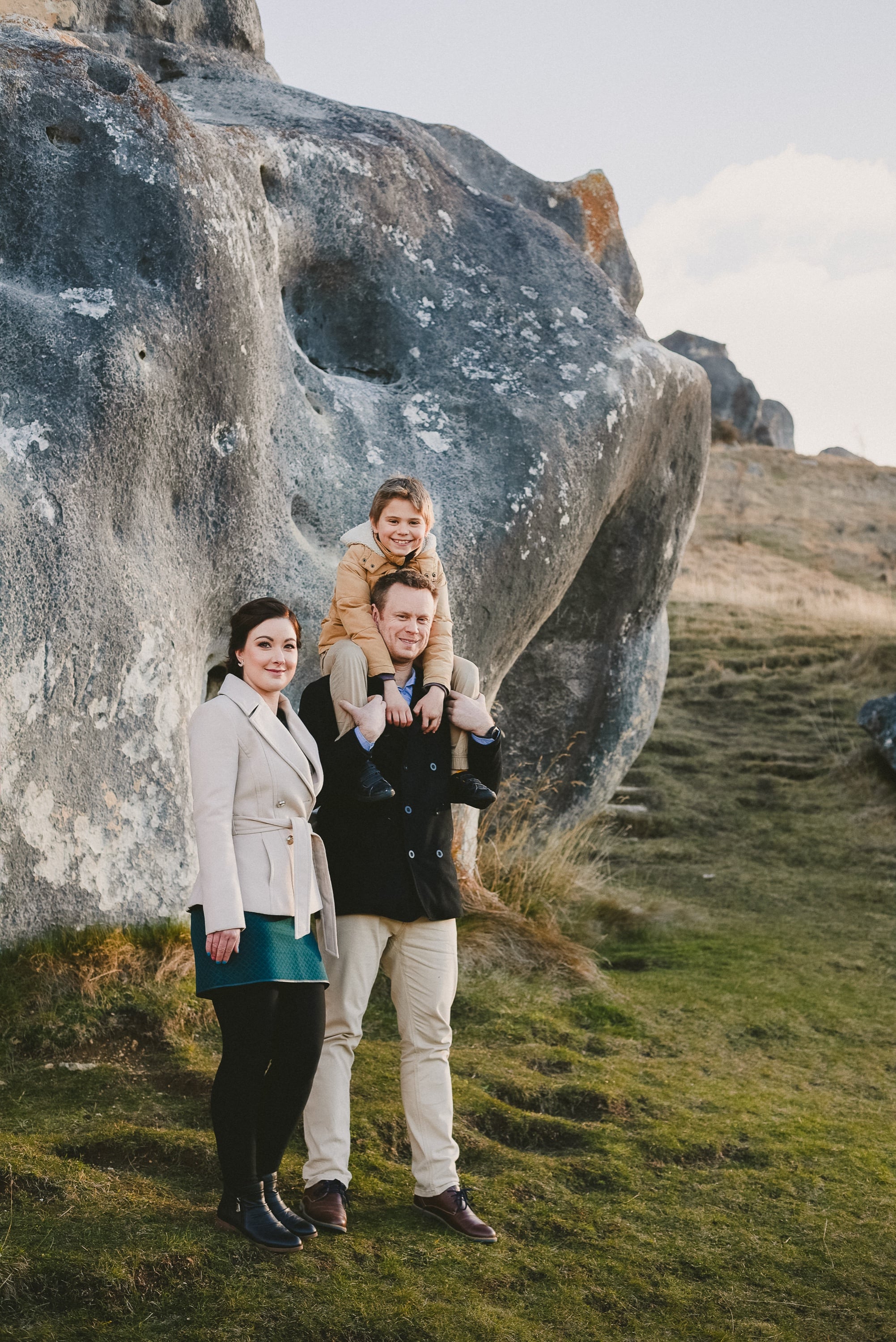 Family of three standing among boulders.