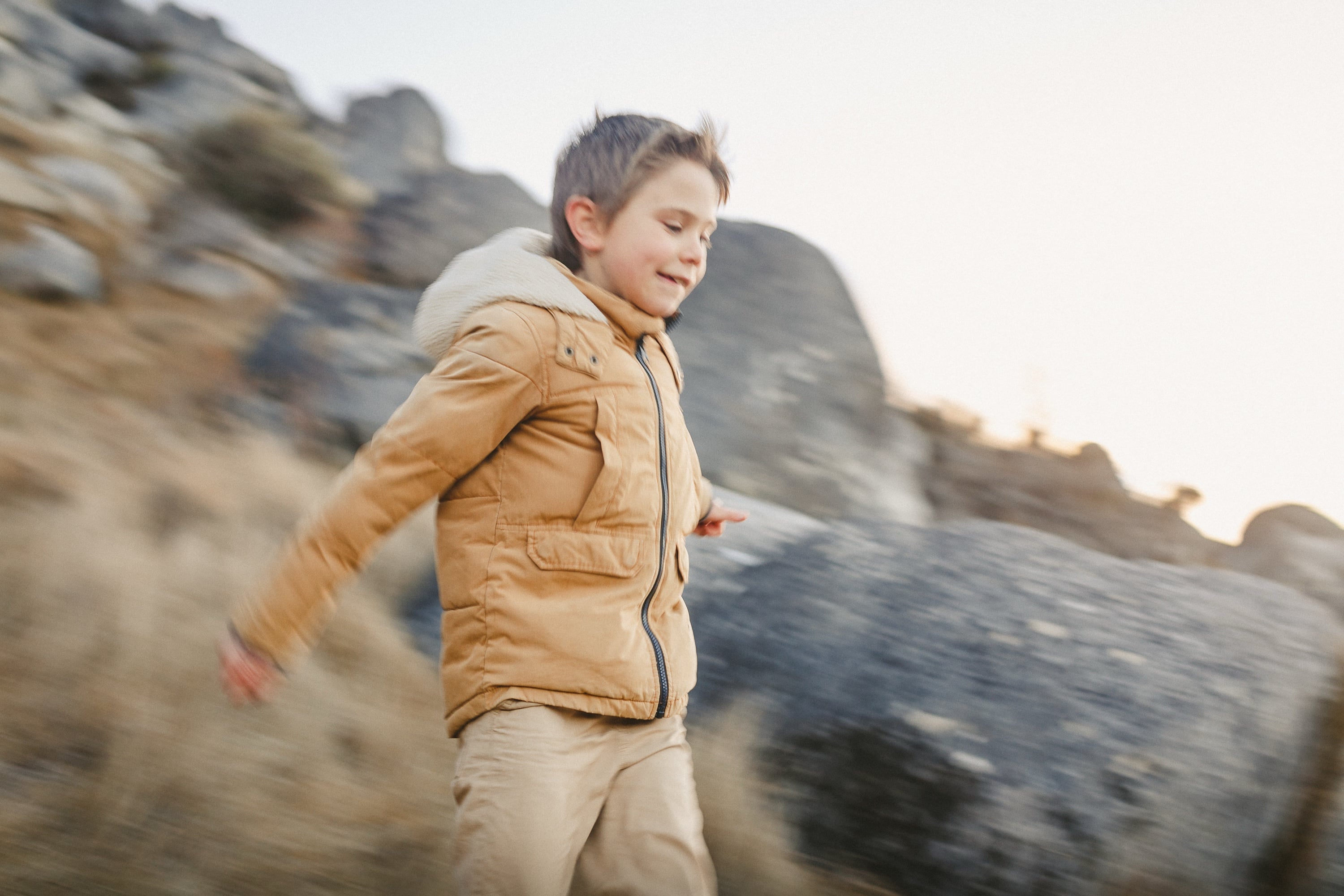 Boy running through golden tussock.