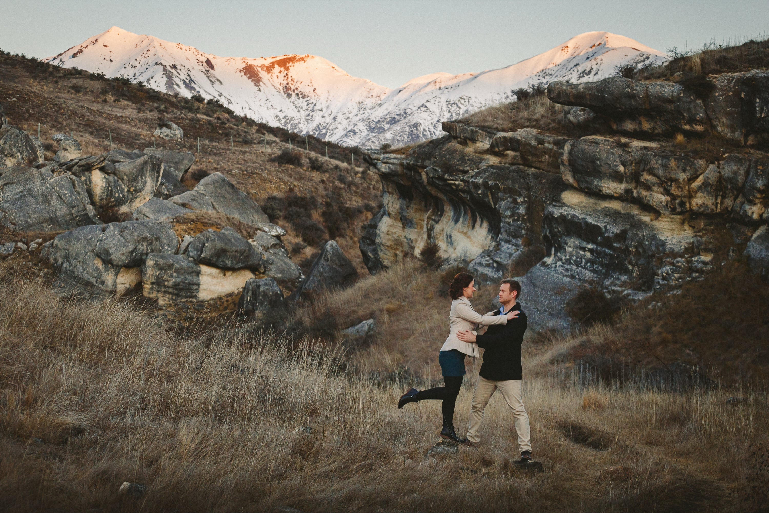 Couple dancing in a high-country valley below snowy peaks.
