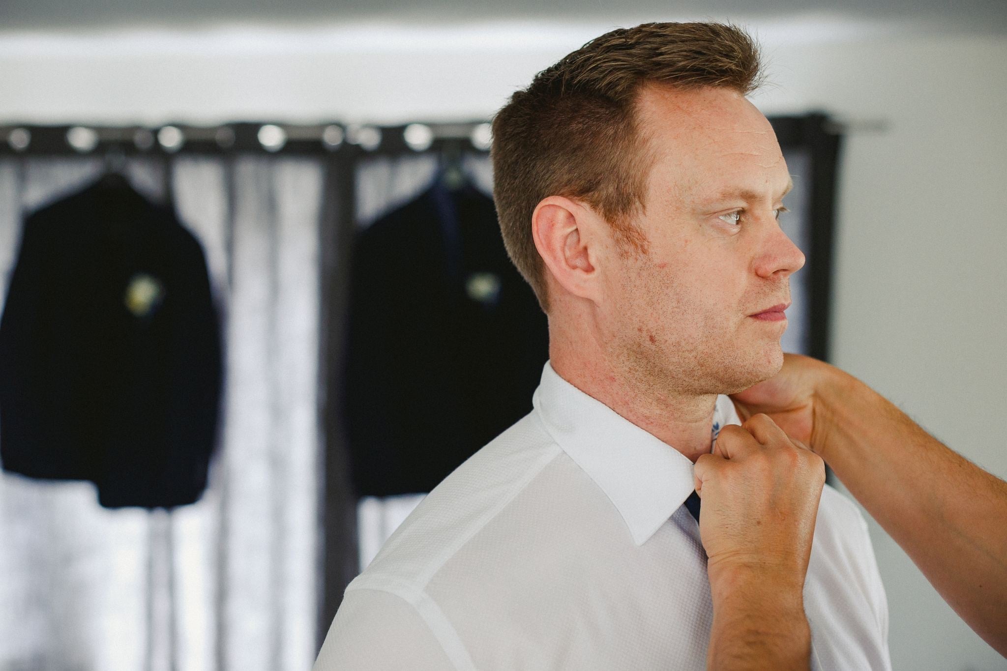 Groom having his tie adjusted.