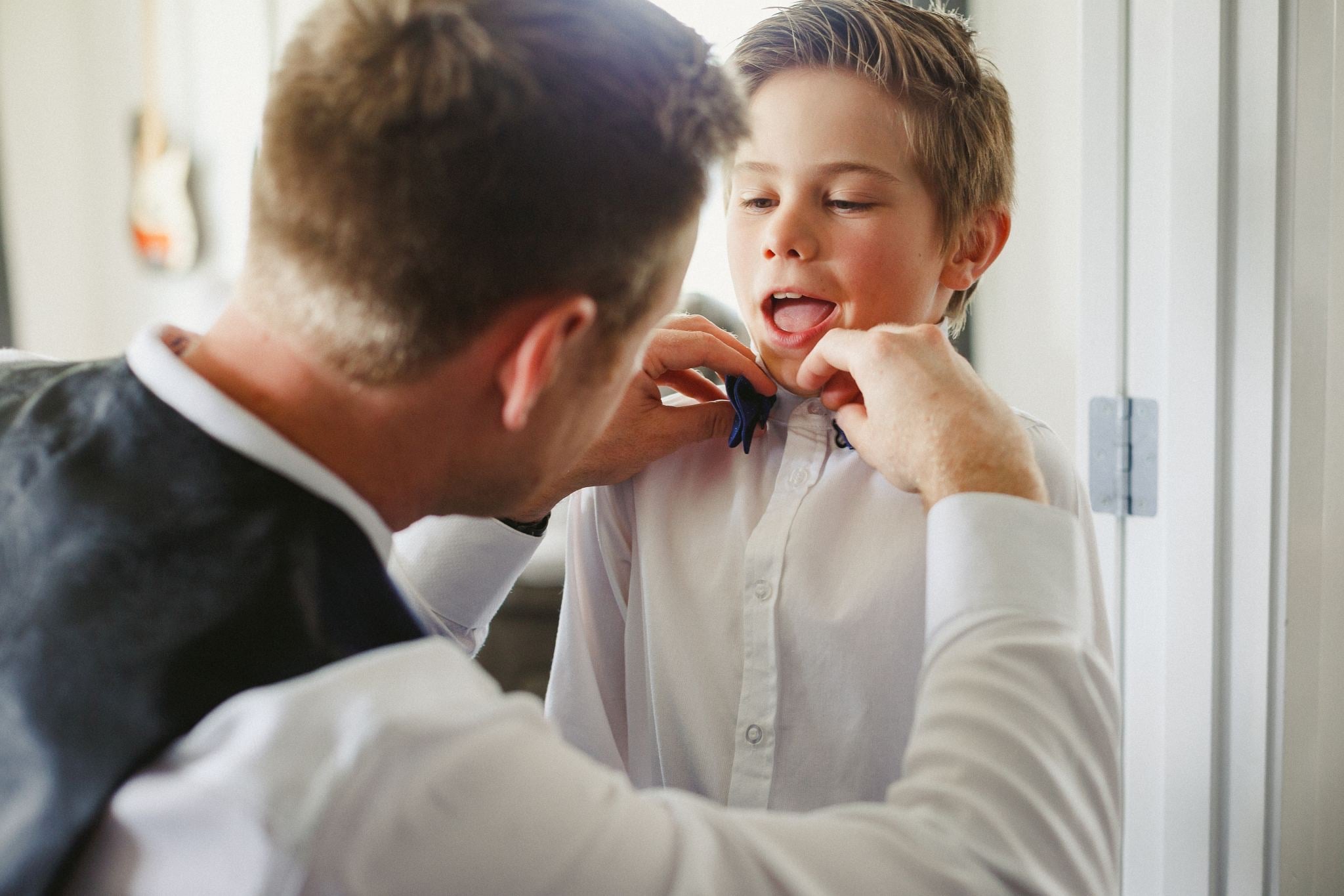 Groom helping a young guest with his bow tie.