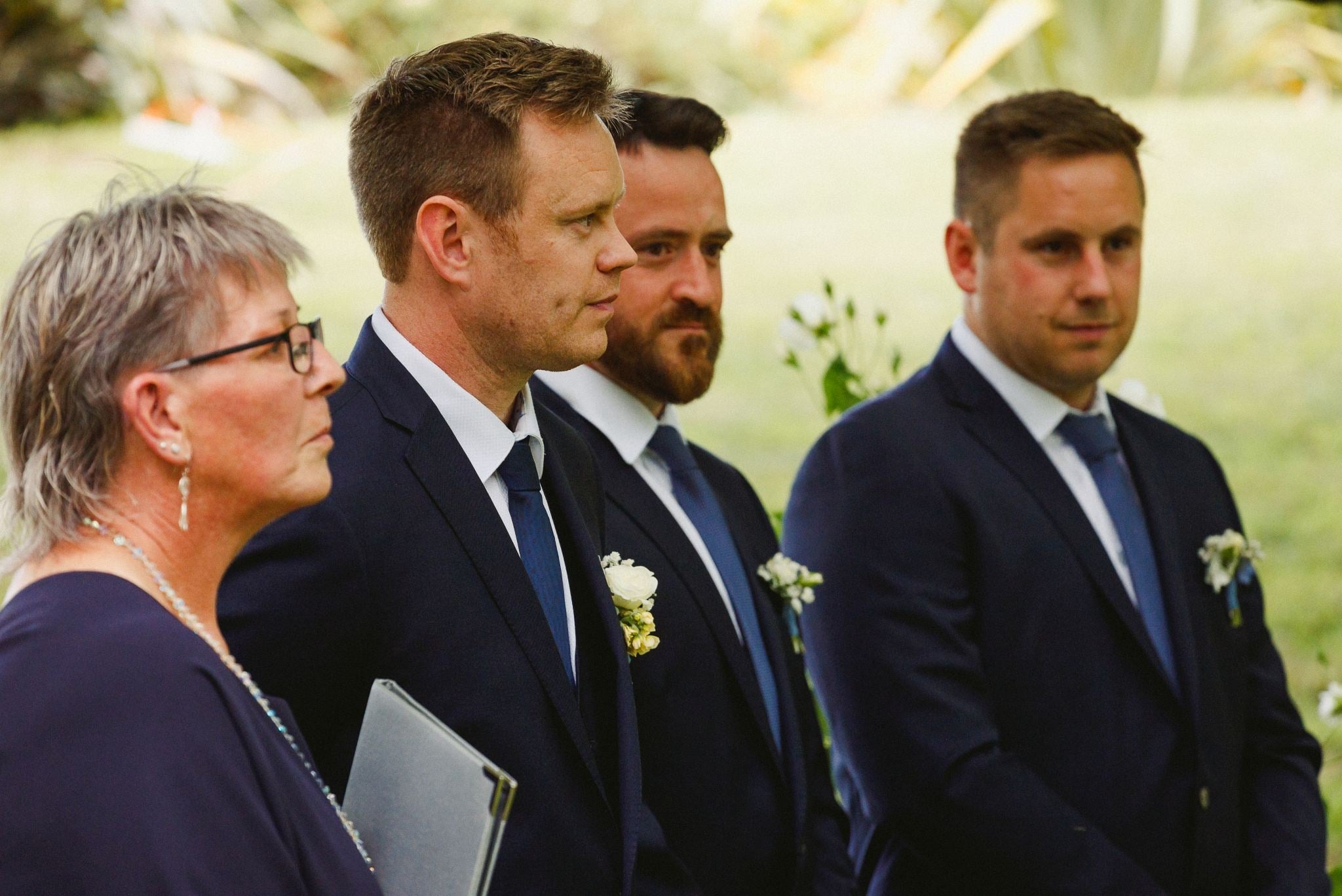 Groomsmen and celebrant watching the vows.
