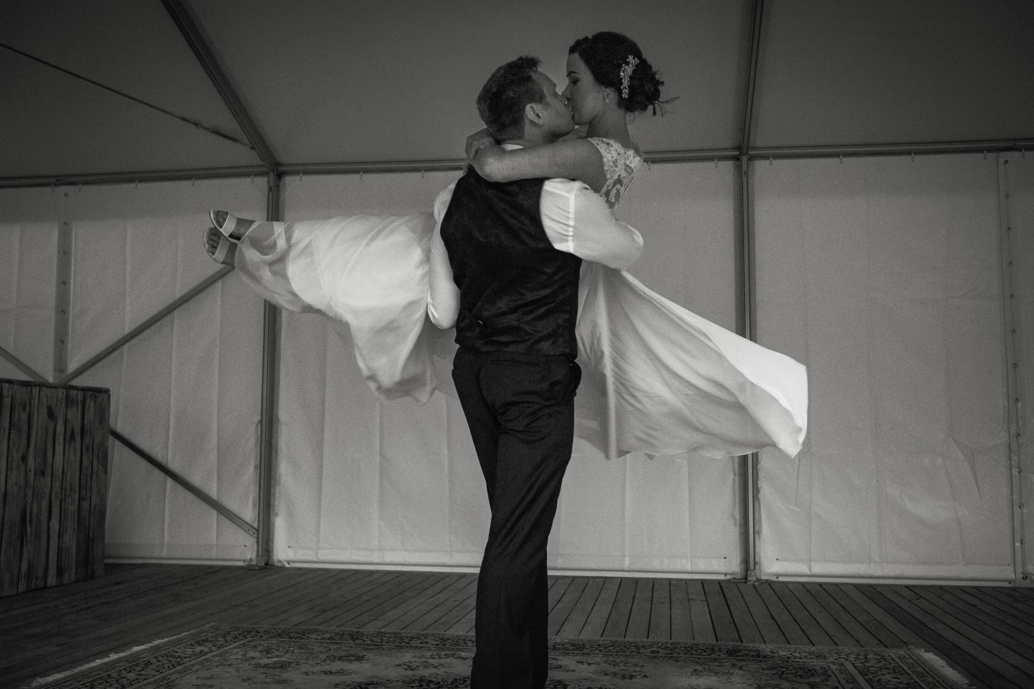 Groom lifting the bride on the dance floor, black and white.