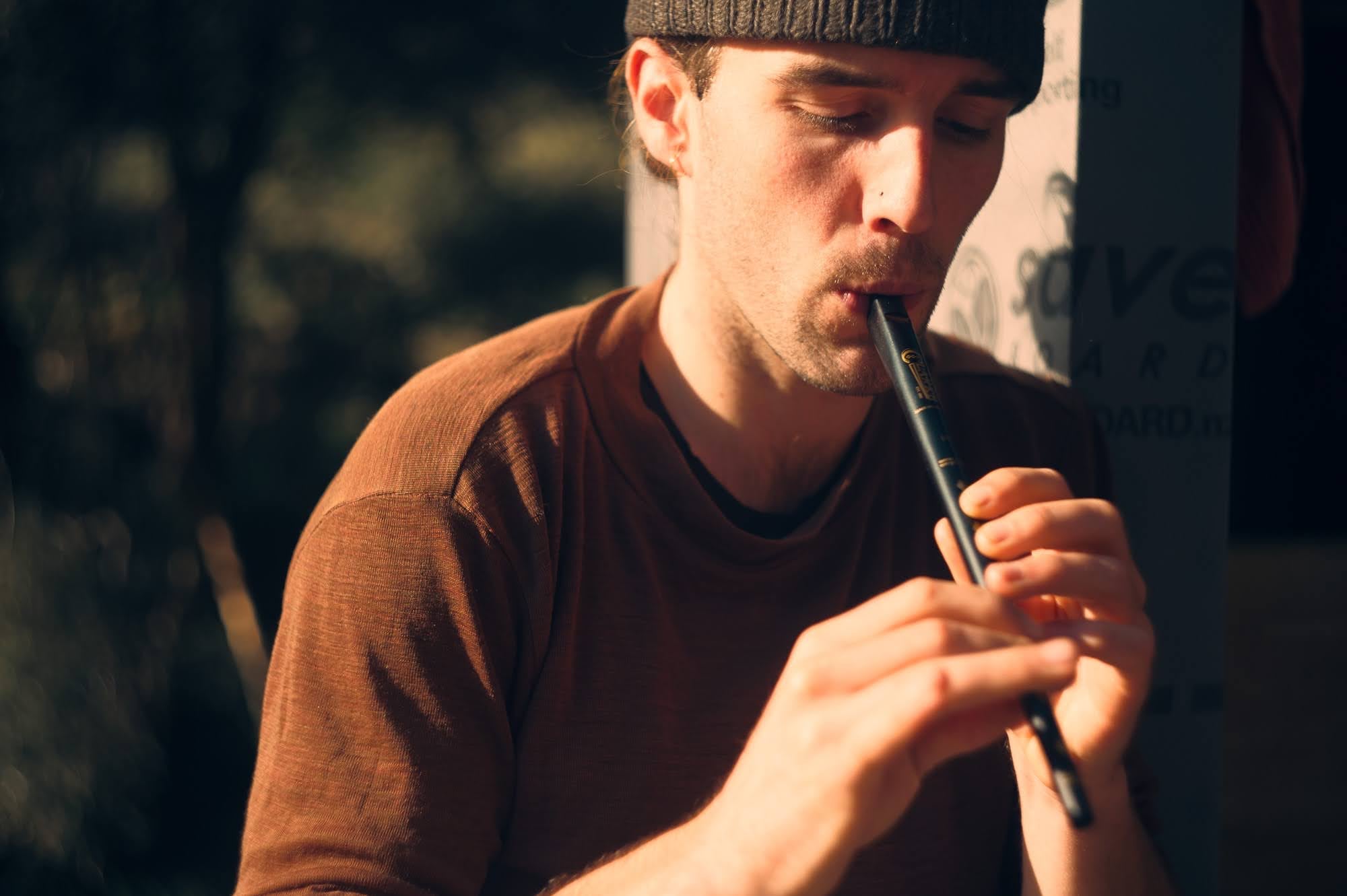 Man playing a tin whistle in warm light.