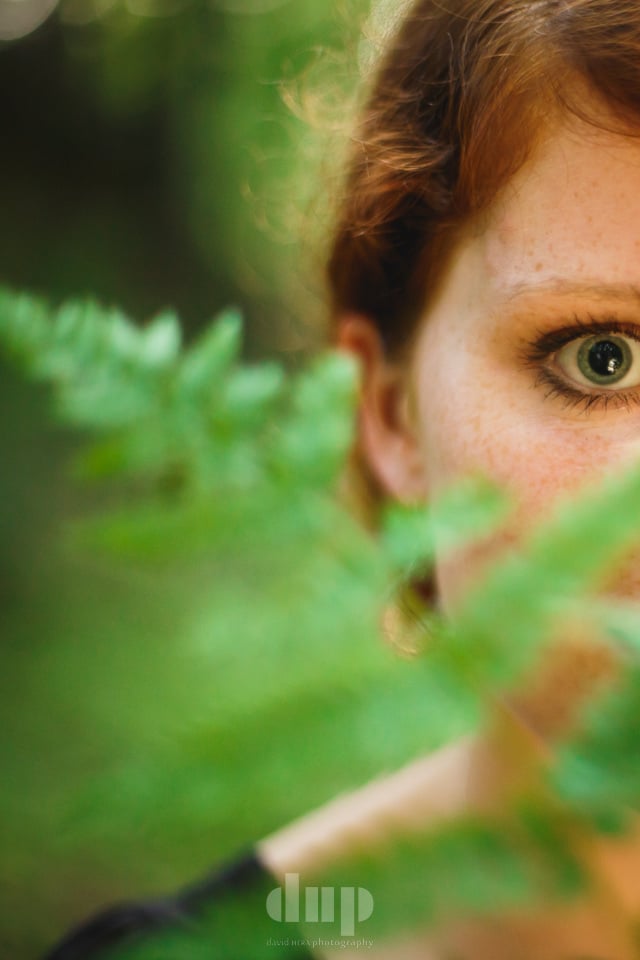 Woman’s eye framed by a fern frond.