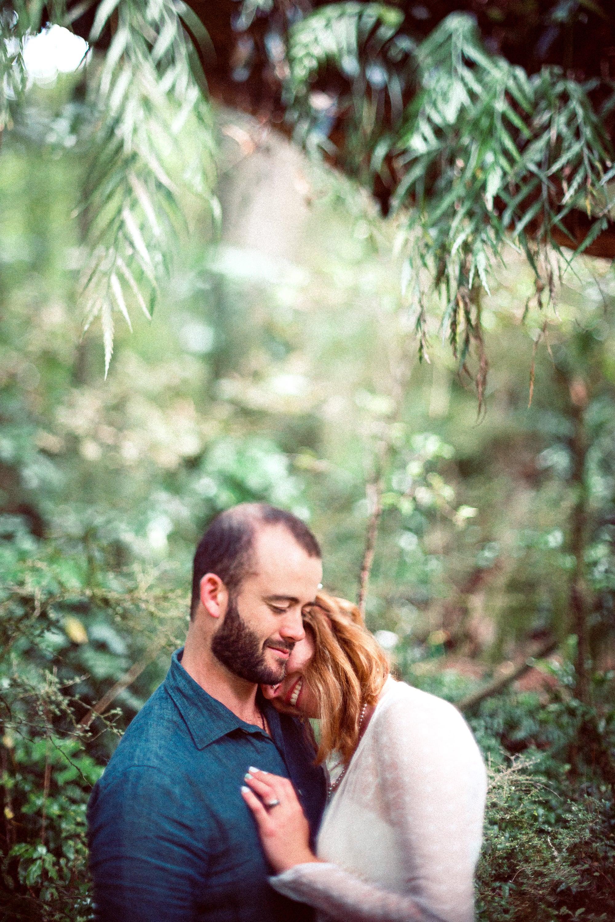 Couple embracing among ferns.