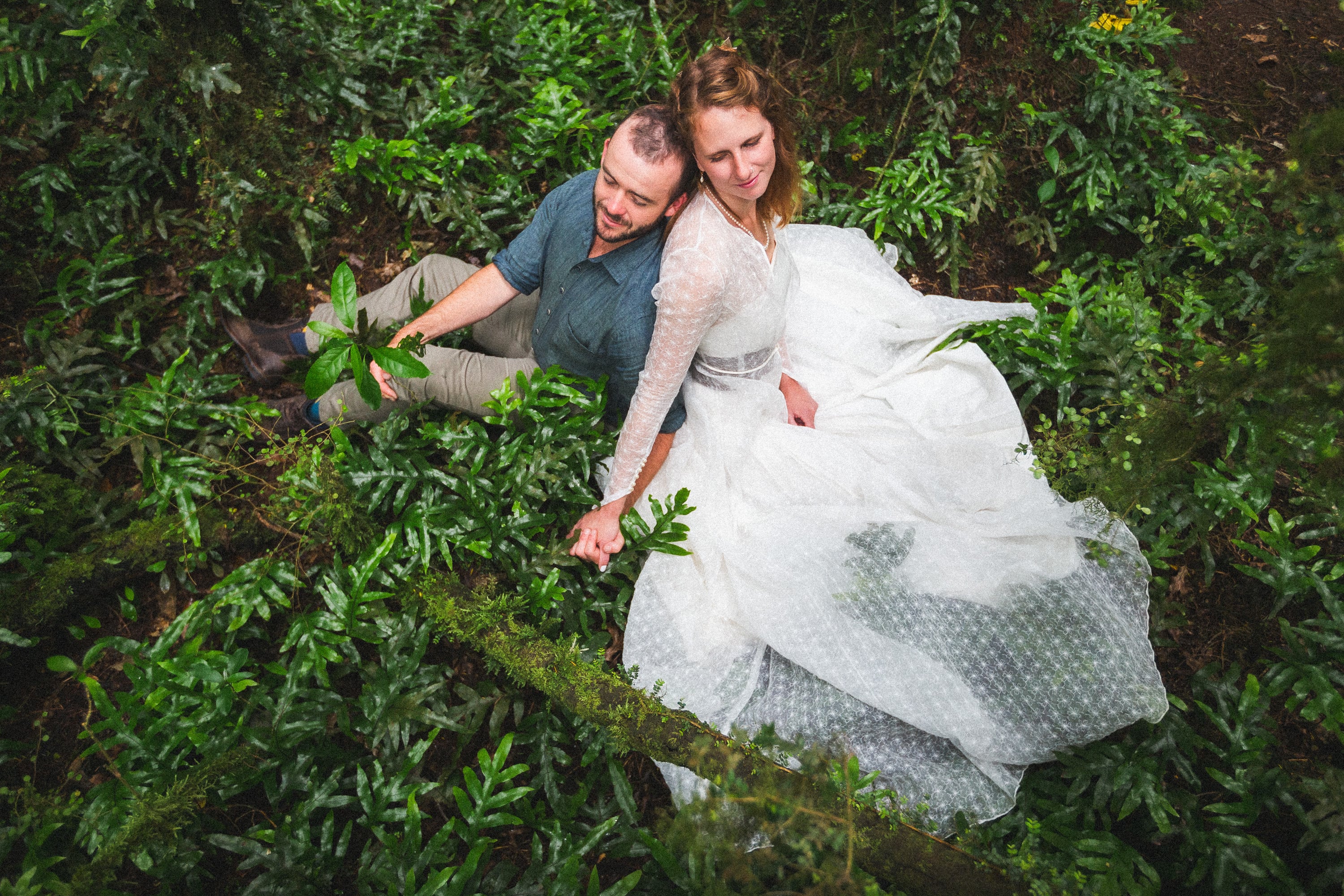 Couple lying together in a bed of ferns.