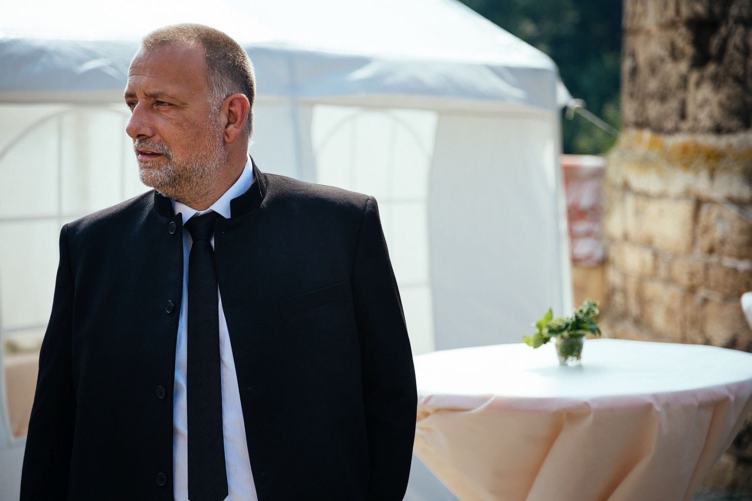 Guest in a dark suit at a garden reception.